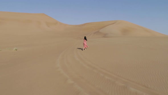 Aerial view of attractive woman using red dress at a desert landscape, U.A.E.