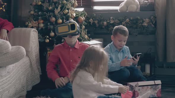 Sweet Children Play with Christmas Presents on Wooden Floor