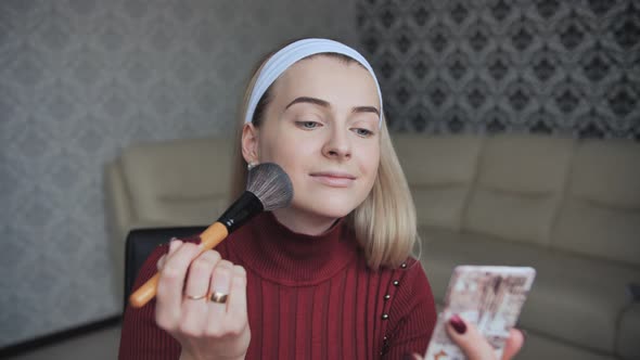 Blonde Applying Facial Powder to Herself with a Brush