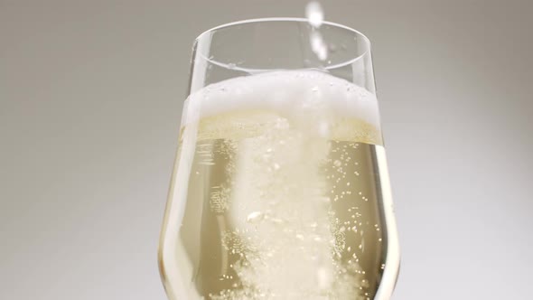 Champagne is Poured Into an Elegant Glass on White Background