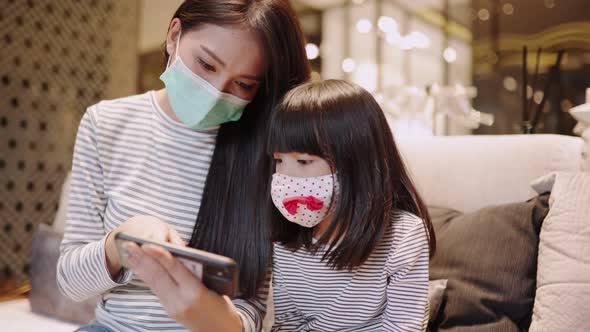 Asian young mother wearing face mask for  kid at home  prevent Covid 19 infection