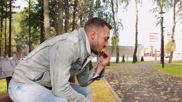 Modern Young Man in Profile Eating a Delicious Hamburger