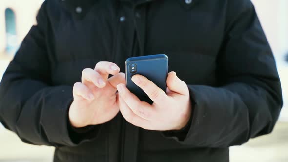 Close Up of Man Hands with Smartphone on Cold Weather