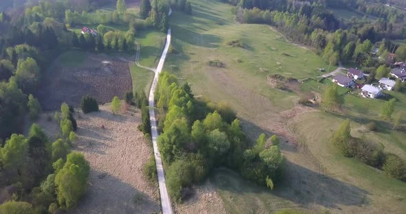 Aerial drone view of a man bike riding in the green countryside hills.