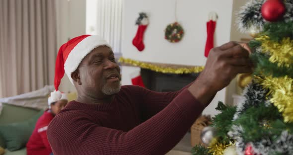 Happy senior african american couple decorating christmas tree in the living room