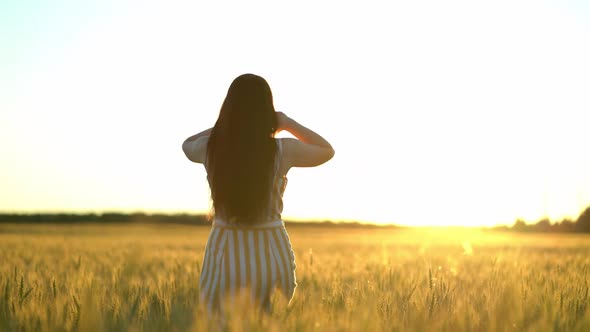 Woman Straightens Hair with Hands in a Wheat Field