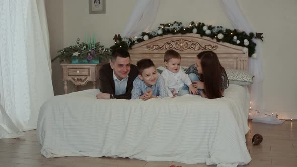 Happy Young Family Lying on the Bed.