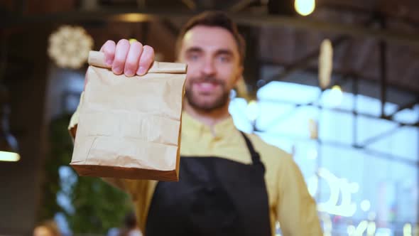 A Paper Food Package with Order in Hands of Barista Waiter