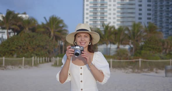 Smiling woman with a retro camera on the beach in Miami