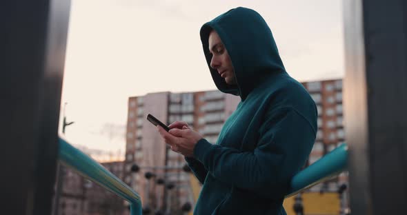 Man on the Sports Ground Using His Smartphone