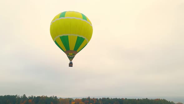 Aerial Drone View of Balloon Flight on a Cloudy Day. A Balloon Flying Low Above the Ground. Autumn