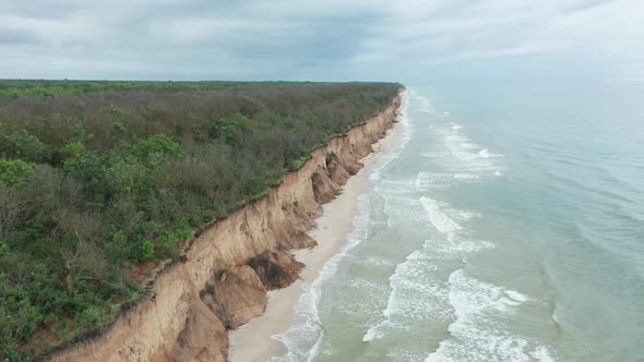 Aerial View of Ocean Waves Beating Against a Rocky Shore on a Wooded Tropical Seaboard