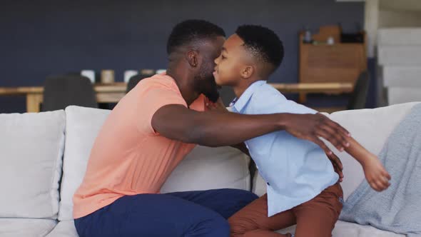 African american father and son embracing on a couch