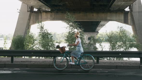 Happy girl in dress and hat is cycling on retro bike