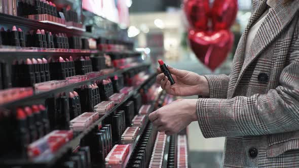 Makeup, Female Buyer in a Cosmetics Store Tests Red Lipstick on Hand During Seasonal Sale, Close-up