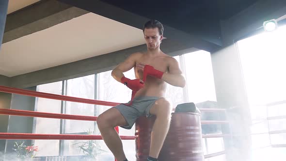 Young Man Boxer Wrapping Red Bandages in the Gym