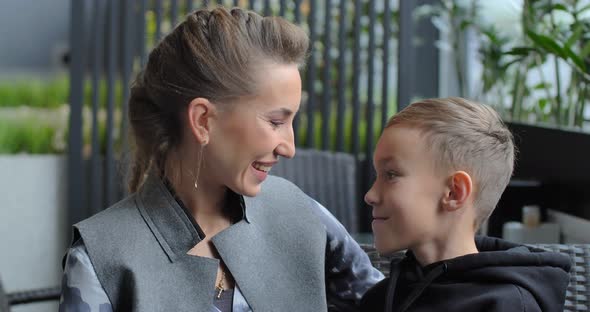 Little Boy and Mom Sitting Indoors and Having Fun Talking