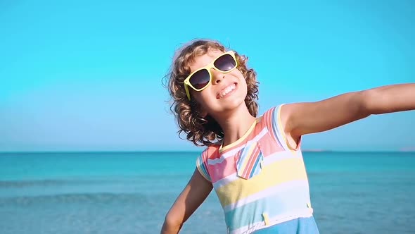 Happy Child with Open Hands against Blue Sea and Sky Background