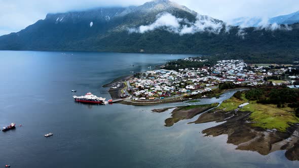 Panoramic aerial view truck left of hornopiren, Chile. Ferry parked at the dock, mountains with clou