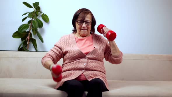 Old Granny Training With Dumbbells On Home. Senior Woman Workout Weight Lifting.