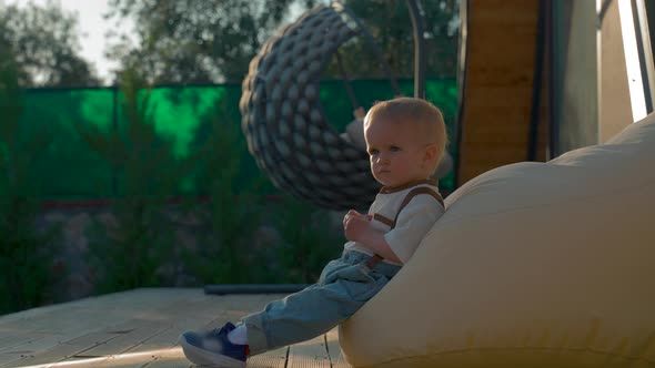 Sweet Blond Toddler Rests Leaning on Bag Chair in Yard