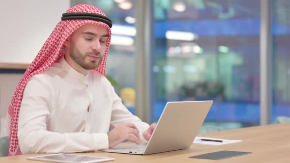 Serious Arab Businessman with Laptop Looking at Camera