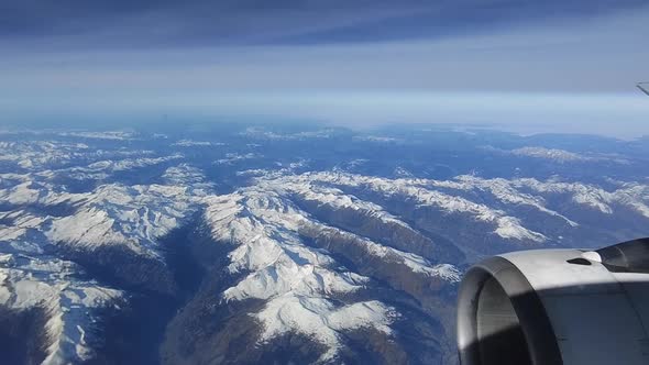 Looking through the window aircraft during flight and seeing a snow covered European Alps mountain r