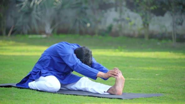 Indian man doing Folded Leg Forward Bend Yoga Pose or Triang Mukha Eka Pada Paschimottanasana