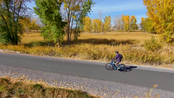 Senior man cycling along a paved nature trail in autumn - aerial view