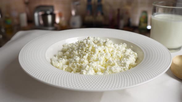 Fresh cottage cheese with sour cream in white plate rotates