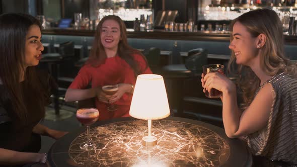 Three Happy Women Sitting at the Small Table in Bar