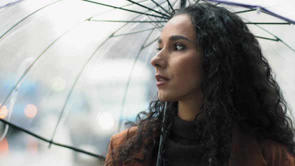 Portrait of Beautiful Young Girl Pensive Serious Woman Stands in City with Transparent Umbrella in