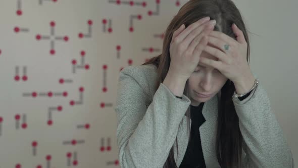 Young stressed woman holding head while sitting in office, job causing headache.