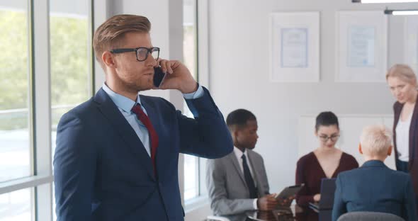 Handsome Businessman Talking on Smartphone in Modern Office