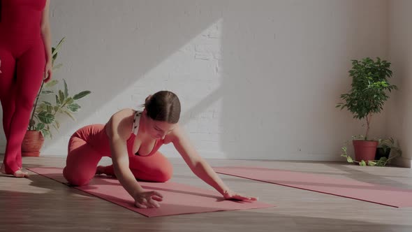 Woman Yoga Trainer Helps the Student to Stretch the Back