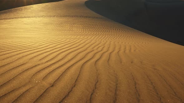 Sand Dune with a Pattern in the Sunset Sun Rays in a Desert. Sand Grains Gliterring. Camera Moving