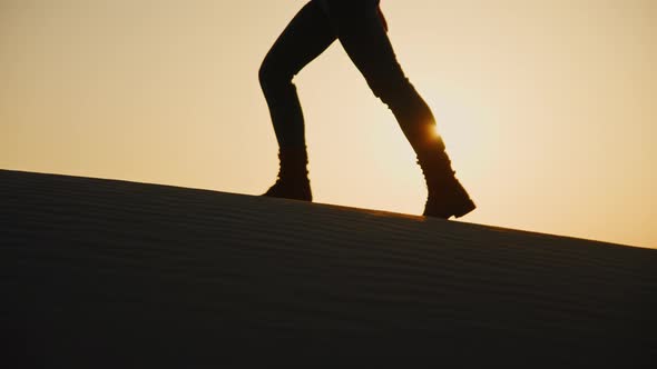 Women's feet walking on a sand dune in the sun