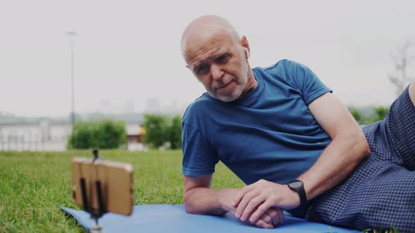 Handsome GrayHaired Old Man Watching Digital Video Content on Smartphone Screen While Sitting on