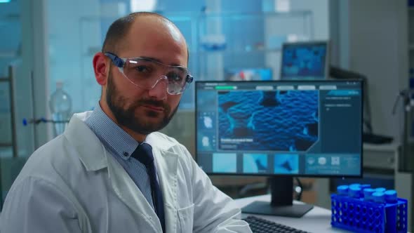 Overworked Scientist with Protection Glasses Looking at Camera Sighing