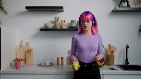 Carefree Elegant Pink Haired Female in Headphones Singing and Dancing in Kitchen