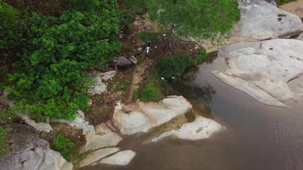 Aerial Shot of a Motocross Rider Driving a Dirt Bike in the Rough Path the River.