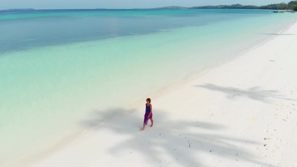 Aerial: Woman walking on white sand beach turquoise water tropical coastline Pas