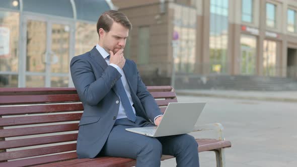 Thinking Businessman Using Laptop while Sitting Outdoor on Bench
