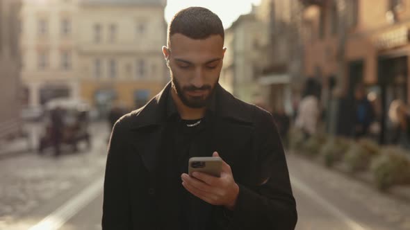 Arabian Businessman Using Mobile While Walking on Street