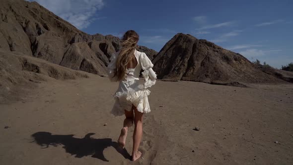 Barefoot Woman Is Running Over Sand To Rocks and Cleft in Desert