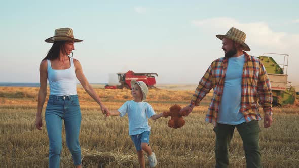 Family of Farmers with Child Walks Through an Agricultural Field and Holding Hands