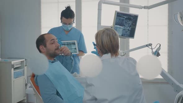 Dentistry Team Showing Teeth x Ray Scan to Patient with Toothache