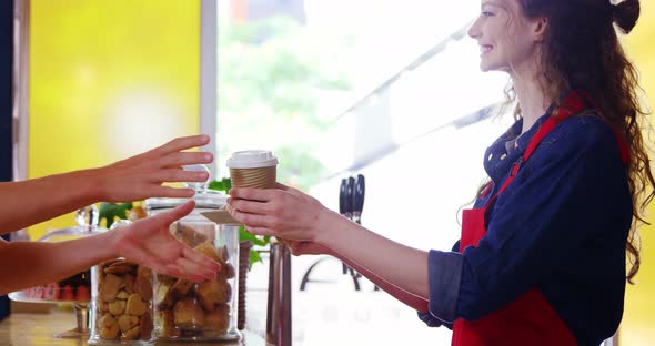 Waitress serving coffee to male costumer at counter