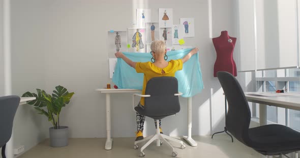 Back View of Woman Fashion Designer Working at Desk in Atelier