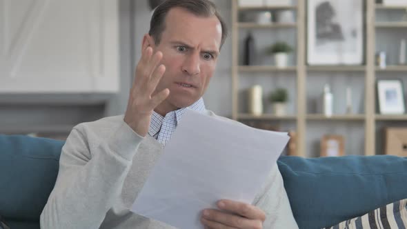 Middle Aged Man Feeling Upset While Reading Documents Contract